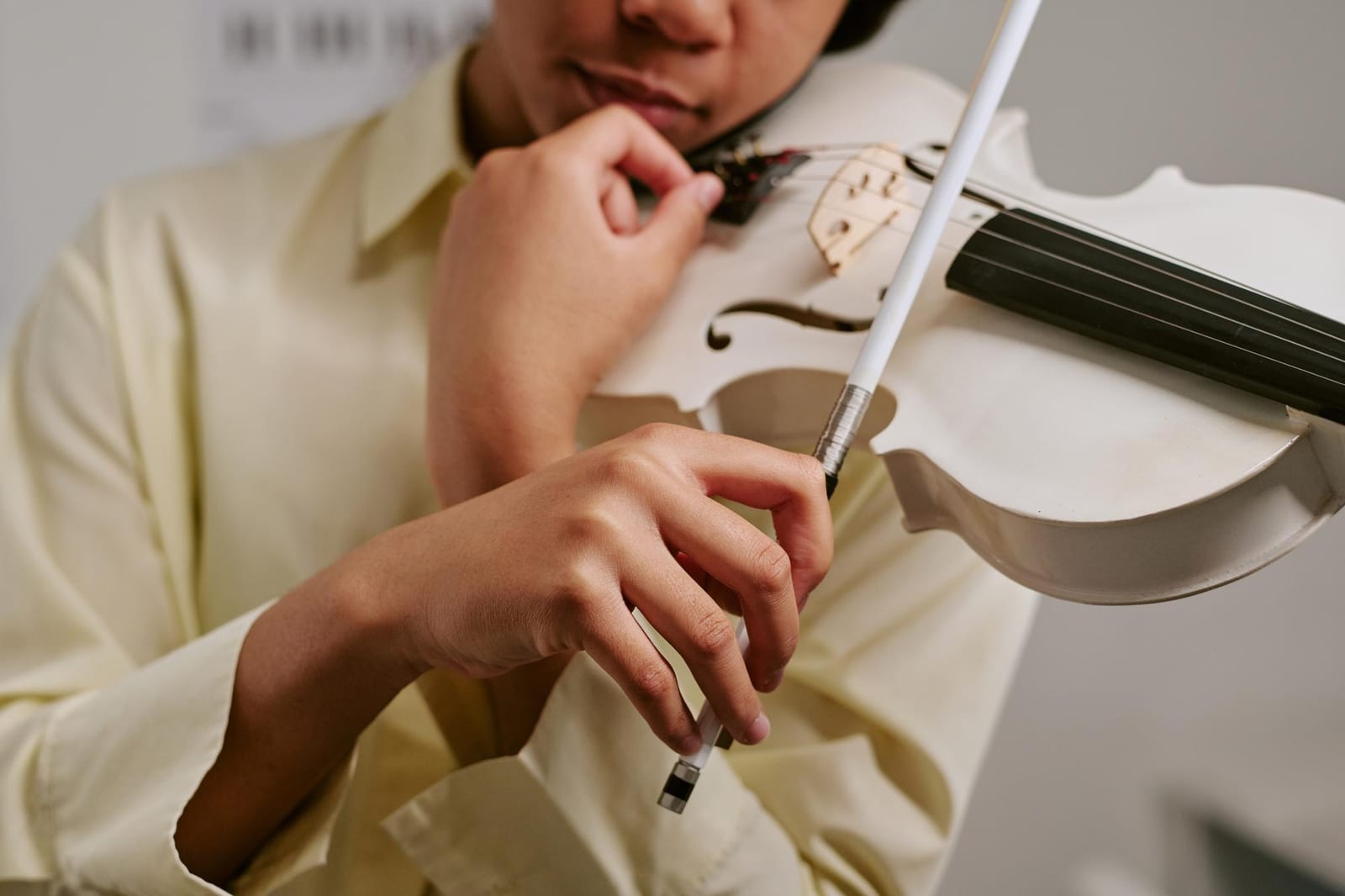Luthier raspando o corpo de um violino sem verniz sob a luz de uma luminária